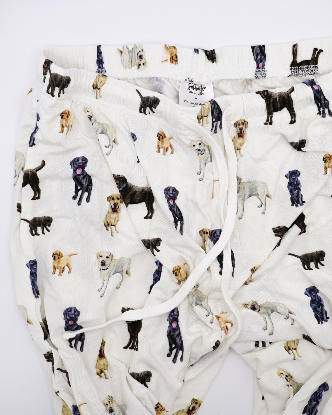 White adult pants with an all-over pattern of black, chocolate, and yellow labs, shown flat on a white background.
