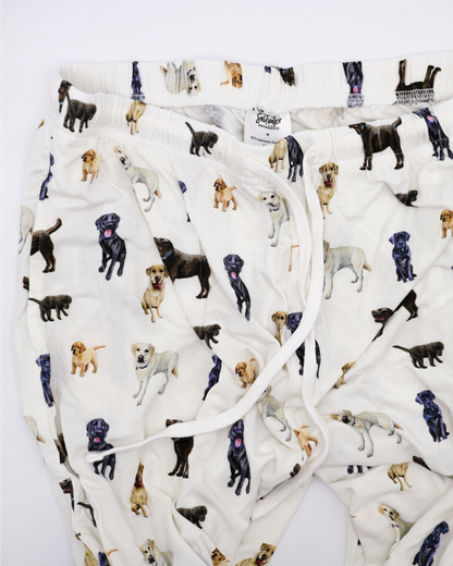 White adult pants with an all-over pattern of black, chocolate, and yellow labs, shown flat on a white background.