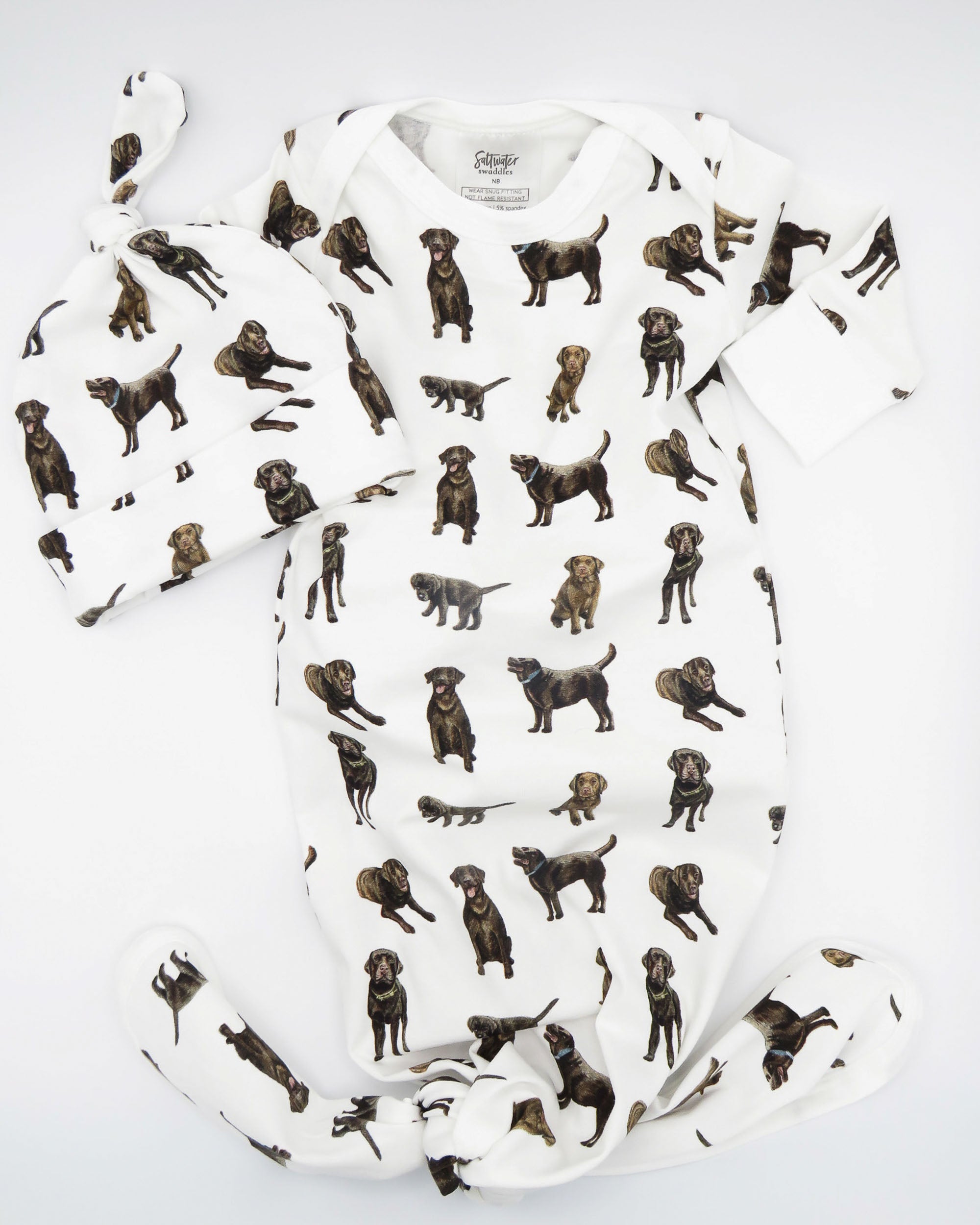 Newborn gown and hat set featuring a cute Chocolate Lab printed on soft white fabric, worn by a sleeping baby.