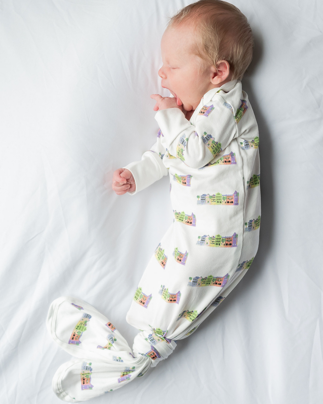 Baby wrapped in cozy Rainbow Row-themed gown and hat, capturing early memories