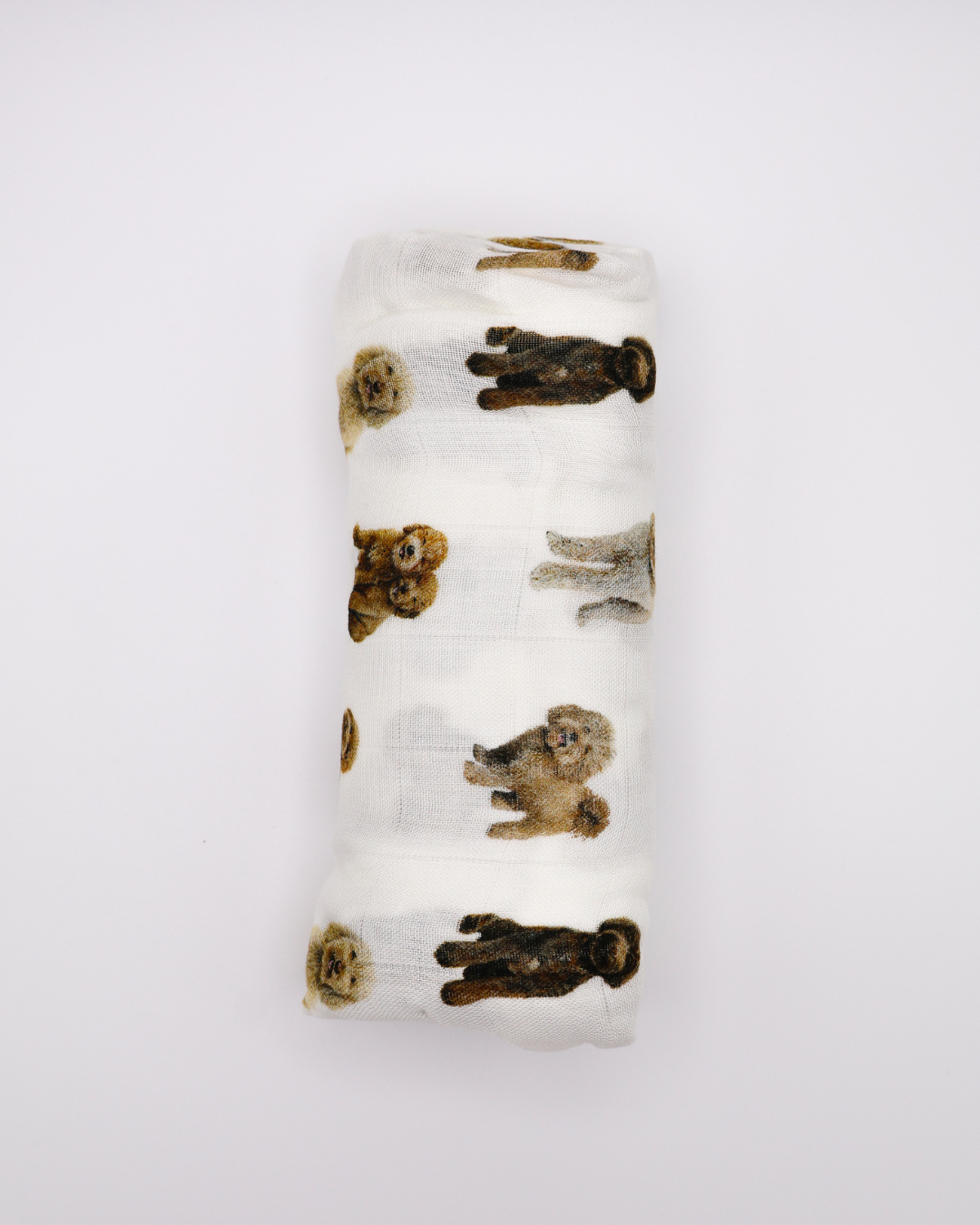 Flat-lay of a rolled muslin baby swaddle blanket covered in realistic sitting and standing goldendoodle dog pattern.