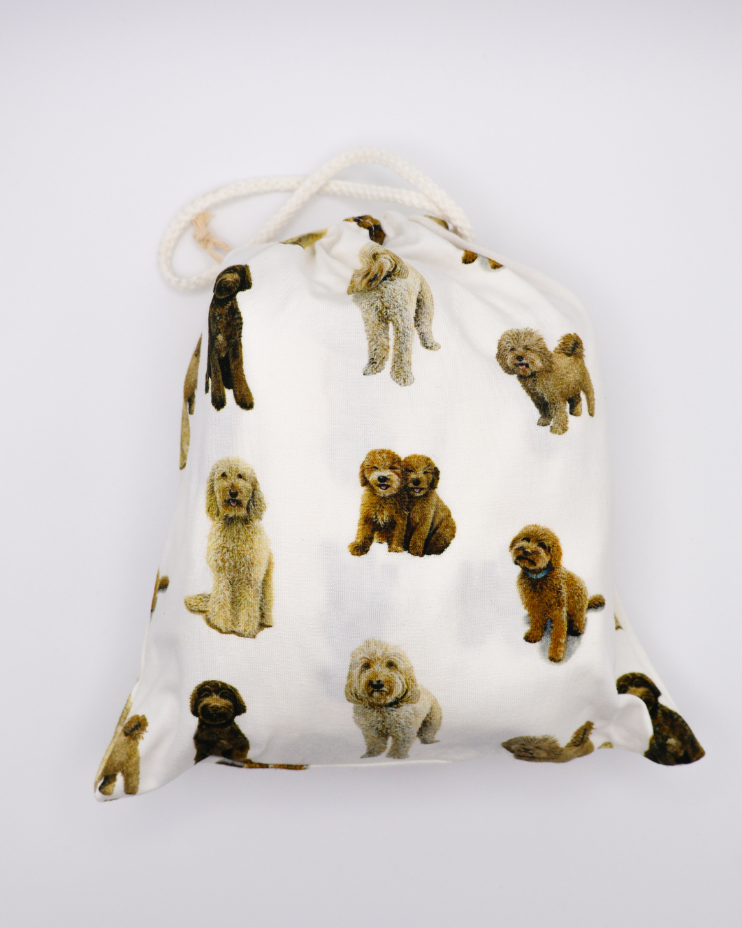 Fitted cotton crib sheet featuring an all-over goldendoodle dog pattern in a crib sheet bag on a crisp white background.