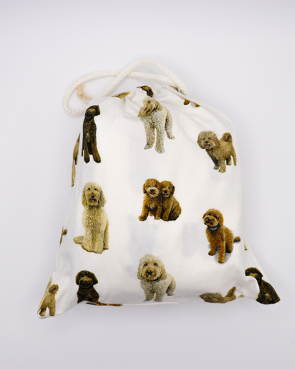 Fitted cotton crib sheet featuring an all-over goldendoodle dog pattern in a crib sheet bag on a crisp white background.