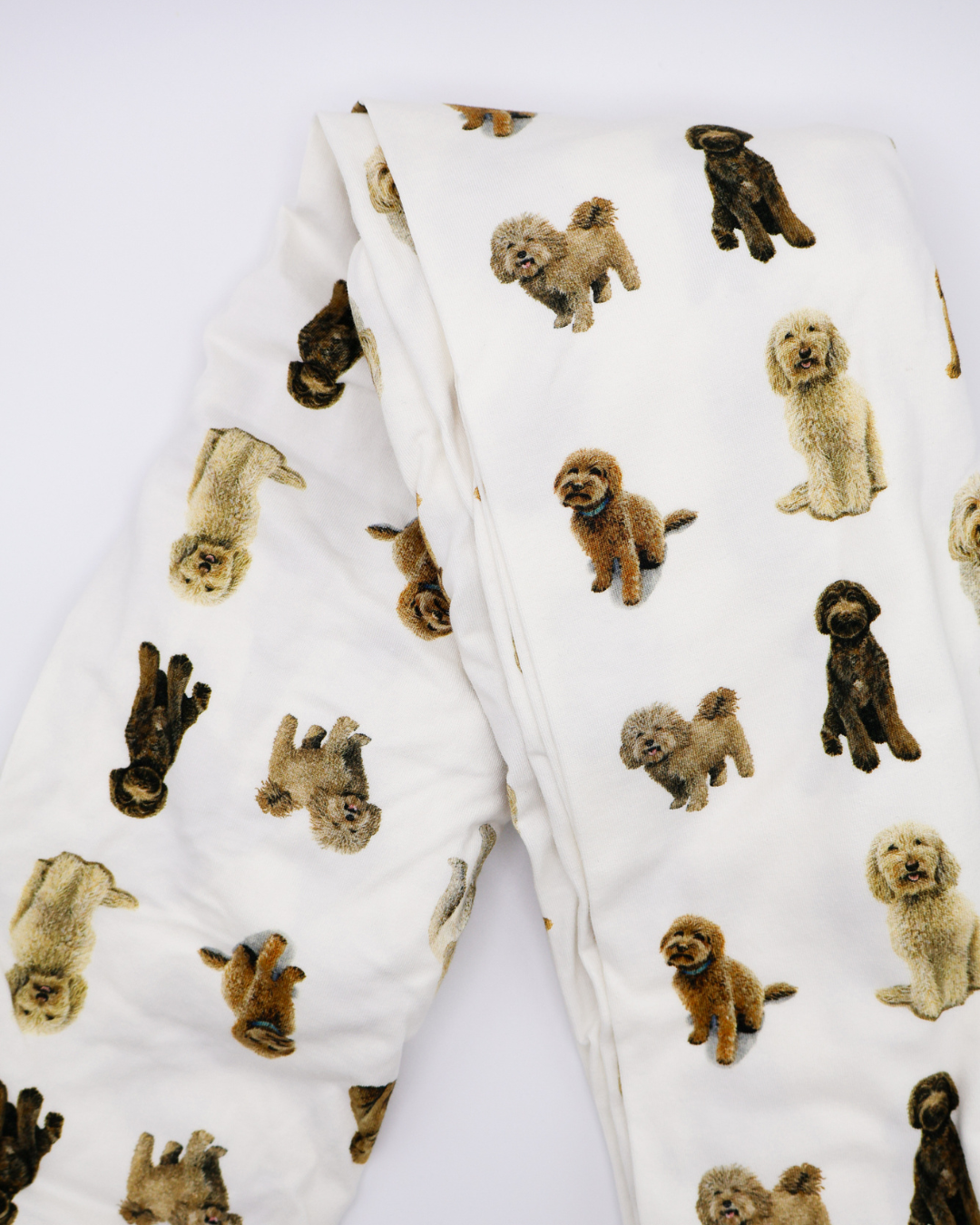 Fitted cotton crib sheet featuring an all-over goldendoodle dog pattern, folded on a crisp white background.