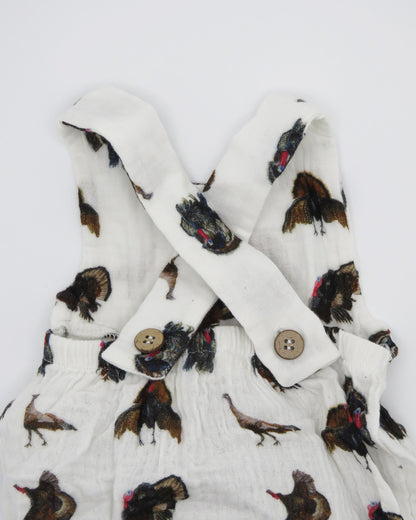 Turkey Trot baby sunsuit in soft white fabric with a playful turkey print, lightweight and comfortable for all-day wear. Perfect for keeping babies cozy indoors or outdoors, ideal for festive fall or Thanksgiving outfits. Displayed flat on white background.