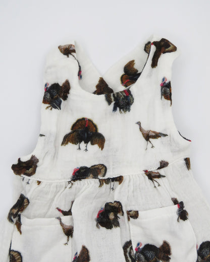 Turkey Trot baby sunsuit in soft white fabric with a playful turkey print, lightweight and comfortable for all-day wear. Perfect for keeping babies cozy indoors or outdoors, ideal for festive fall or Thanksgiving outfits. Displayed flat on white background.