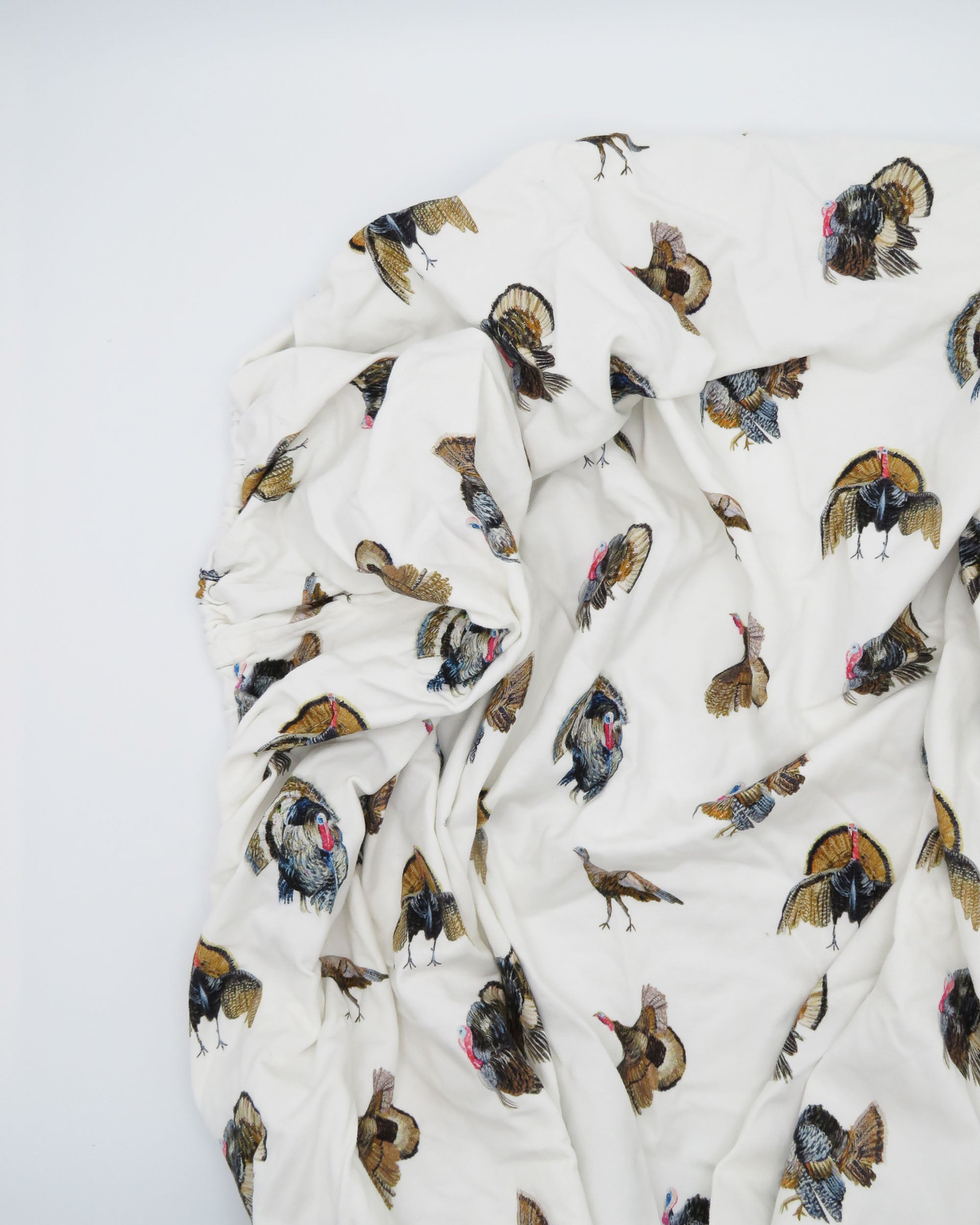 Adorable Turkey Trot crib sheet in soft white jersey cotton, featuring playful turkeys. Displayed on a white background, highlighting cozy and stylish nursery décor—perfect for a turkey-themed nursery.