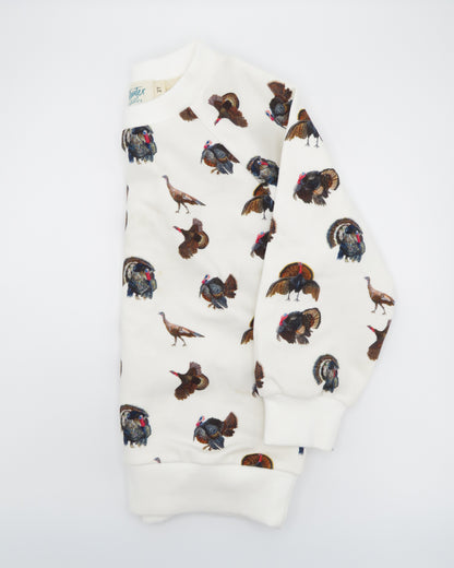 Turkey Trot kids’ drop sleeve sweatshirt in soft white fabric with a playful turkey print, cozy and comfortable for indoors or outdoors. Displayed folded and flat on white background.