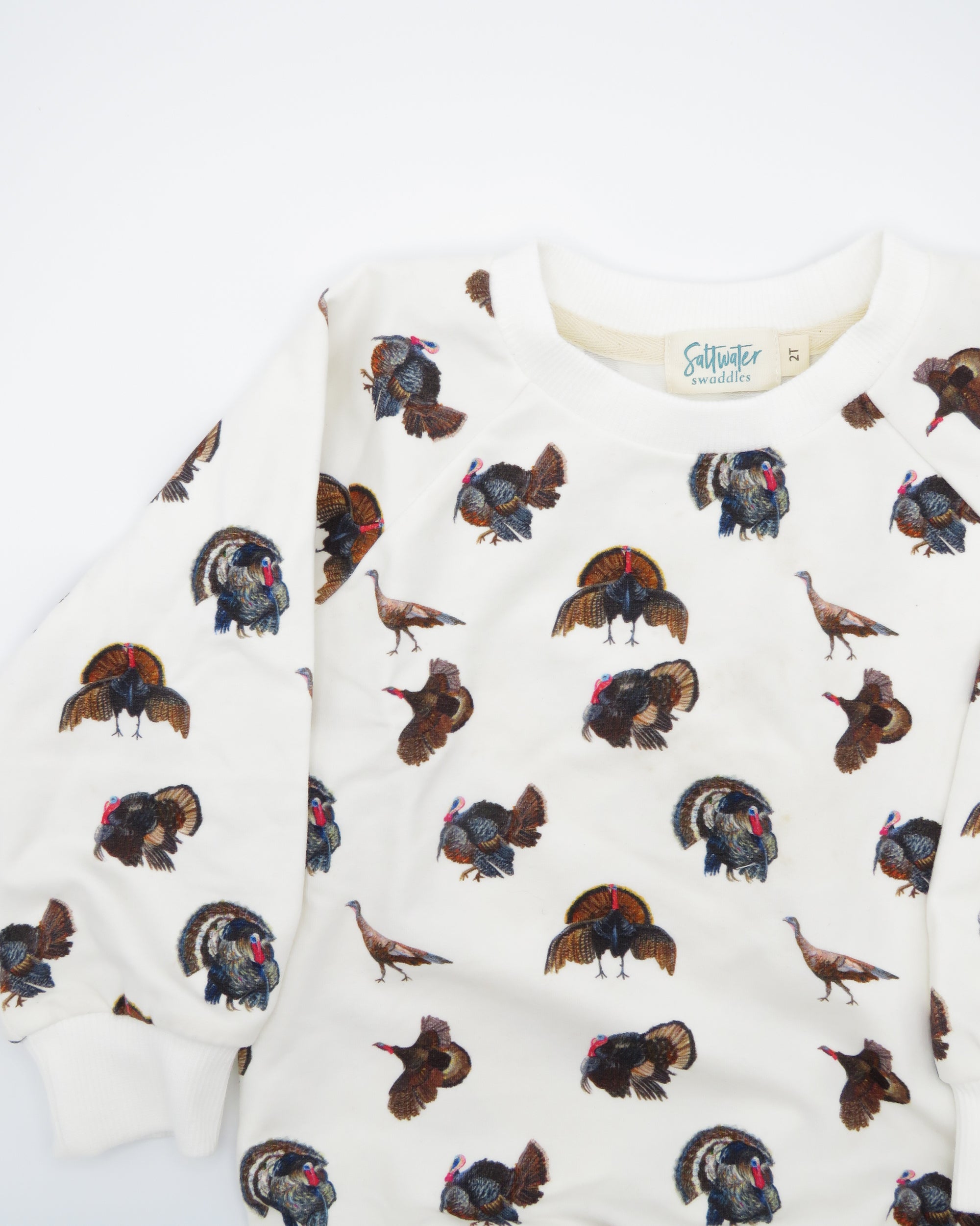 Turkey Trot kids’ drop sleeve sweatshirt in soft white fabric with a playful turkey print, cozy and comfortable for indoors or outdoors. Displayed flat on white background.