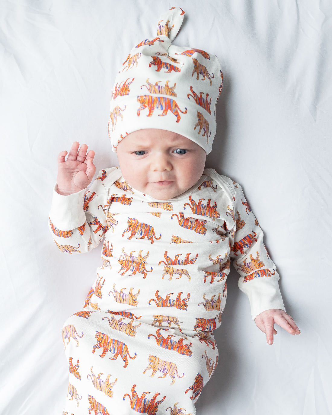 Easy Tiger newborn gown with matching hat worn by a newborn, made from soft white breathable cotton. Perfect for a newborn’s first moments and a must-have for the hospital bag.