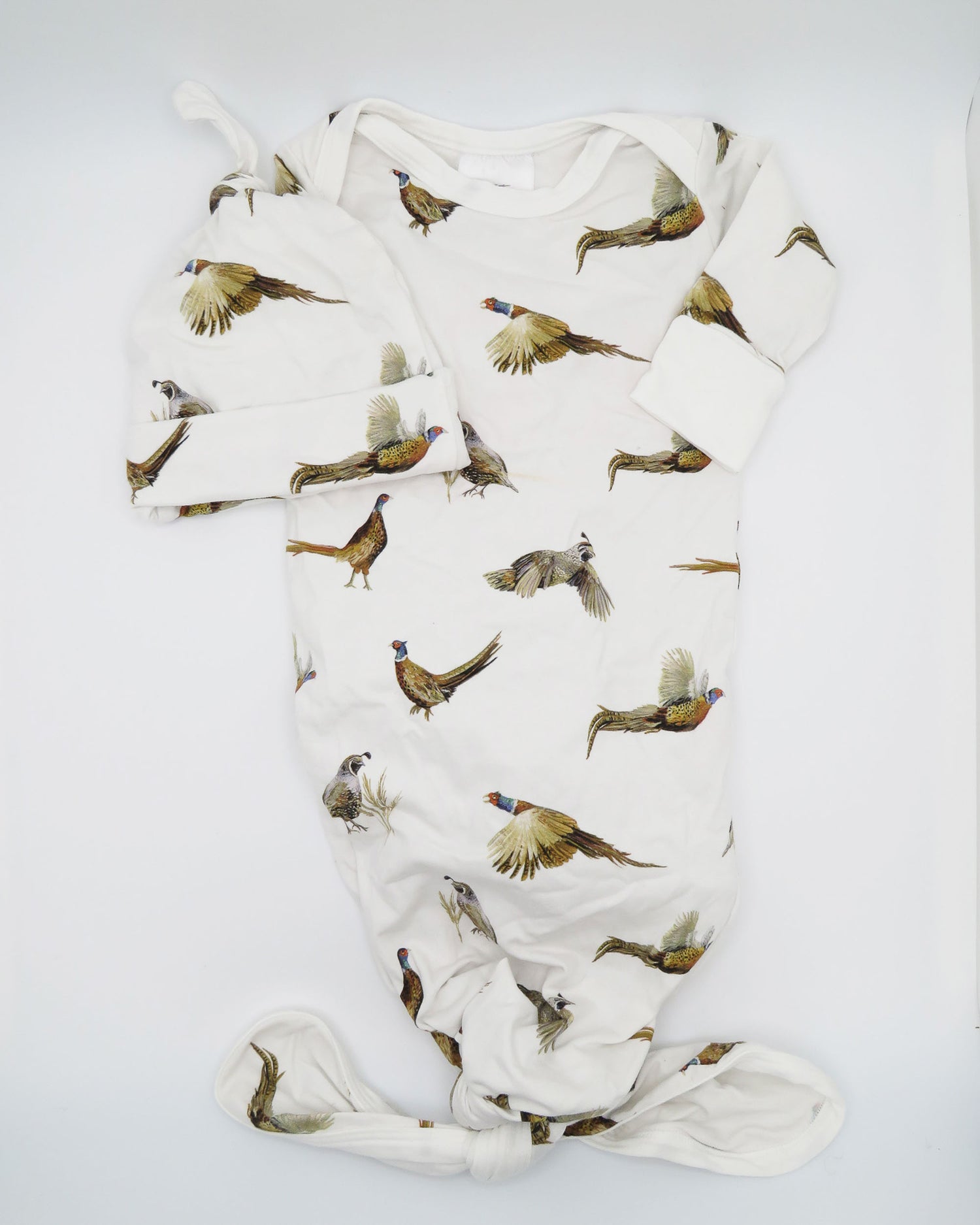 Peasants and Quail Newborn Gown and Hat Set – Soft white fabric, adorable matching gown and hat, perfect for newborn photos and a must-have for your hospital bag. This set is displayed flat on white background.