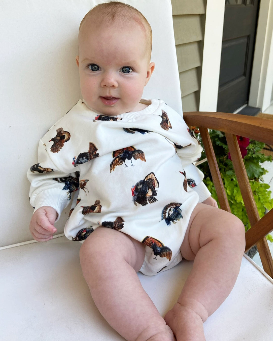 Baby relaxing comfortably in a cozy Turkey Trot sweatshirt romper