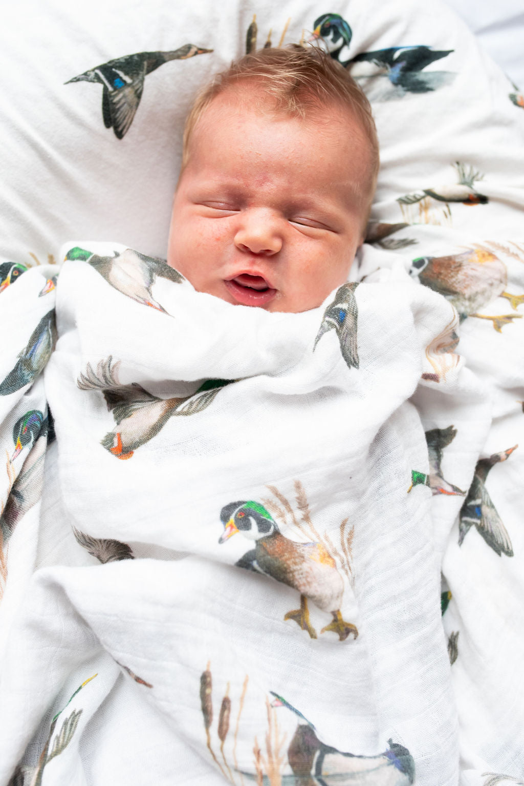 Vibrant pattern of diving ducks on a soft swaddle, perfect for wrapping newborns in style and comfort